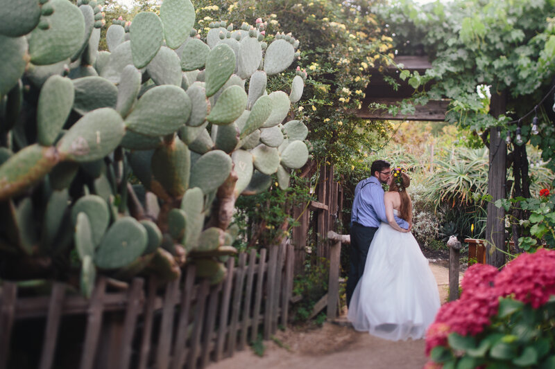 Bride and groom kiss in cactus garden