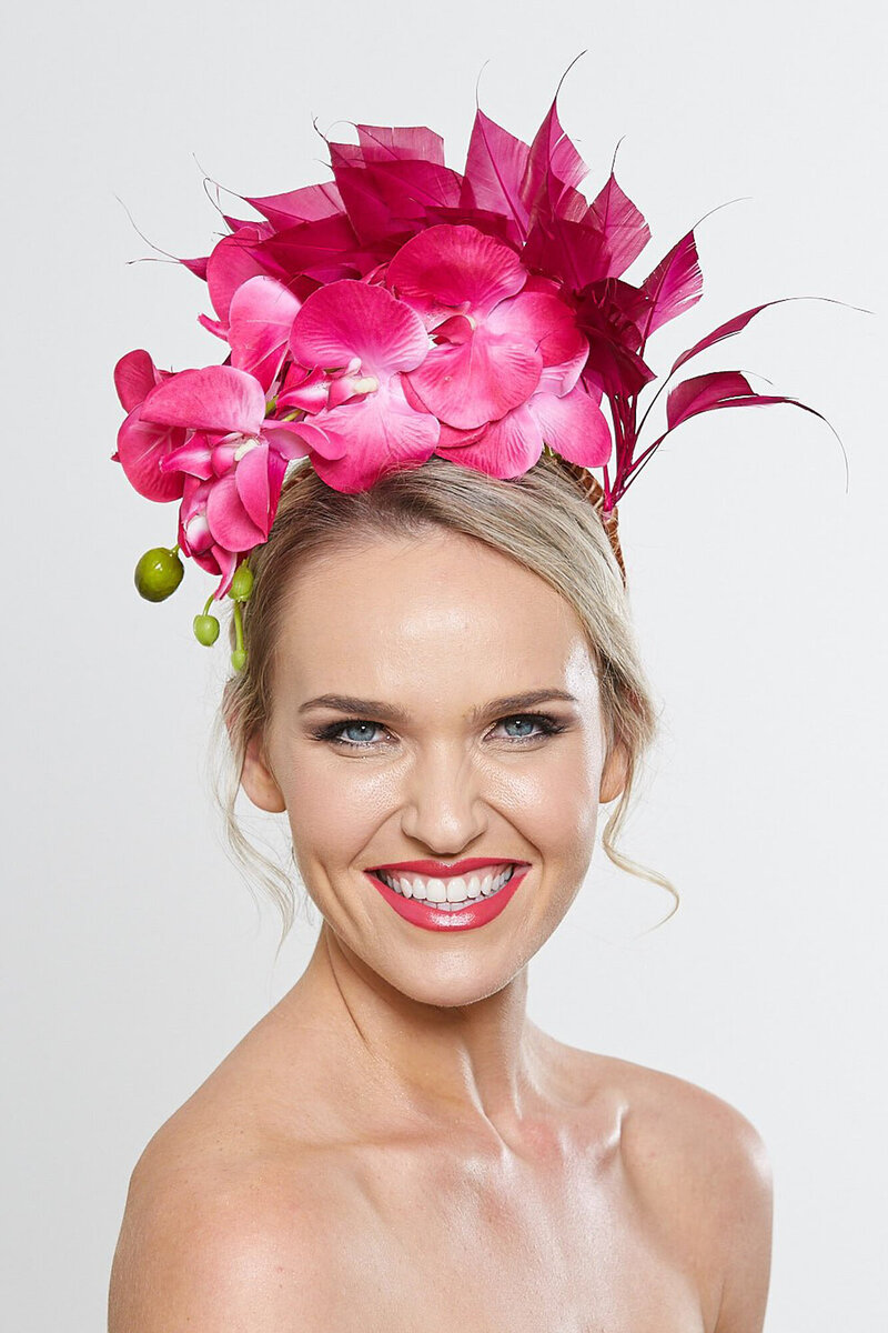 Photo of model wearing pink fascinator against plain background for a product photography shoot