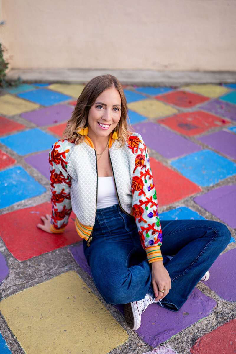 Micaela spinning and laughing in front of a colorful wall at Union Cowork in Encinitas, California