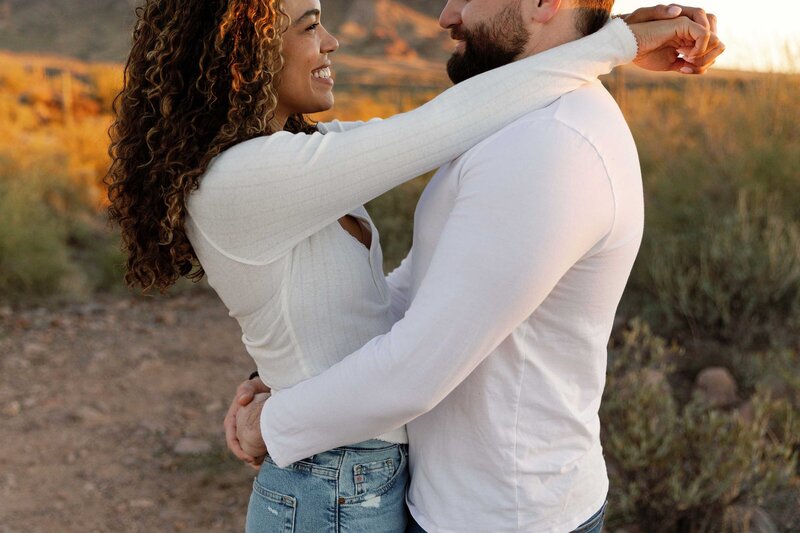 Couple hug and smile at each other in the desert.