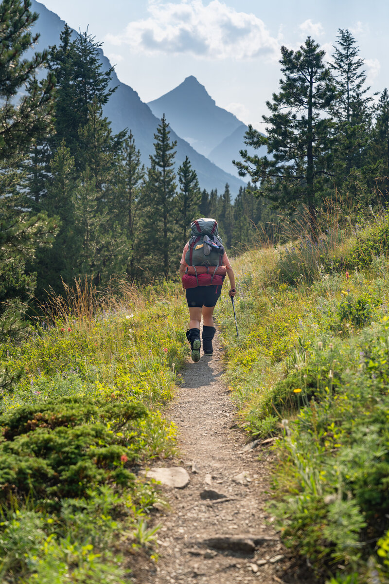 A female backpacker hikes towards Rising Wolf mountain in Glacier National Park in Montana.