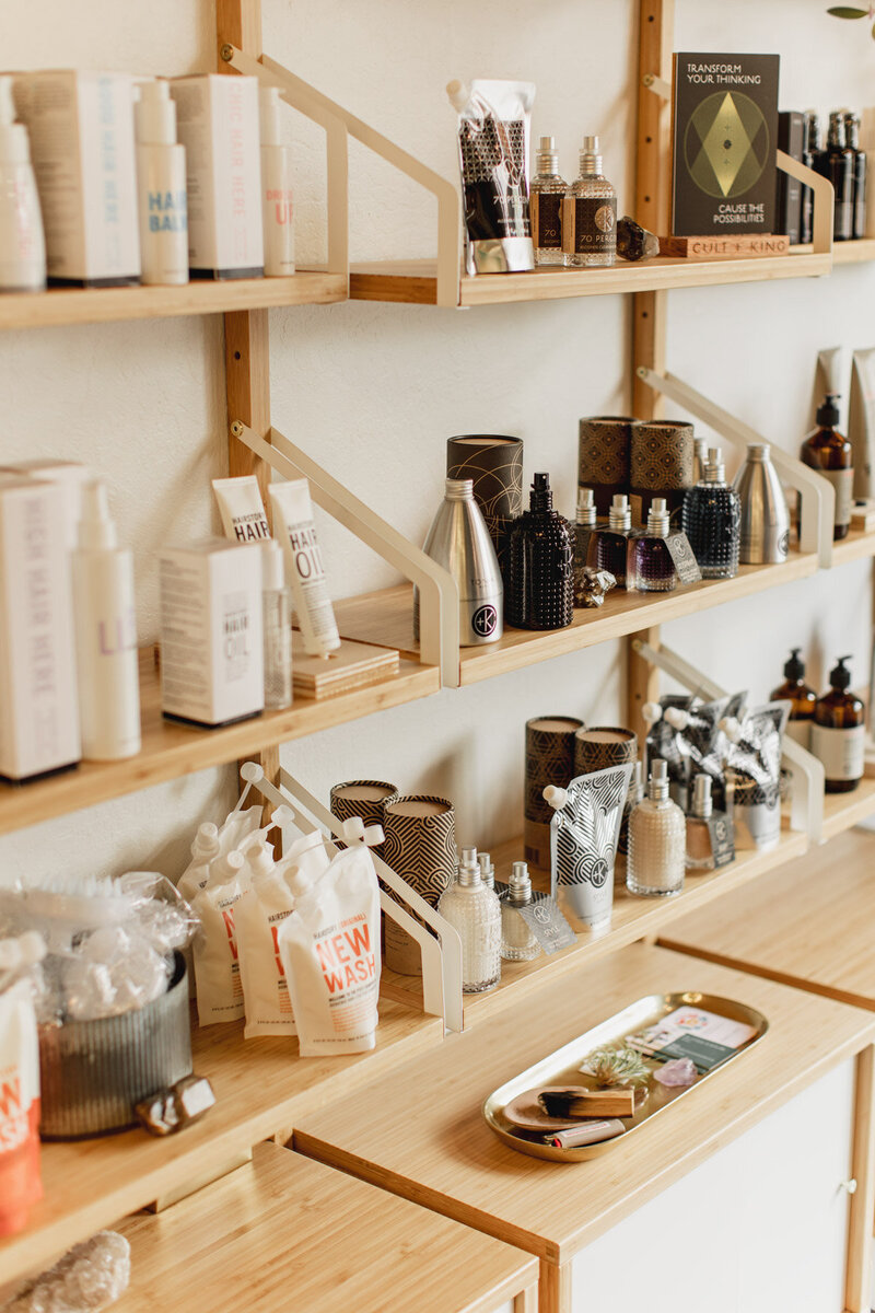 A close up of wooden shelves containing hair care products used by craft hairdressers at The Collective Beauty and Wellness.