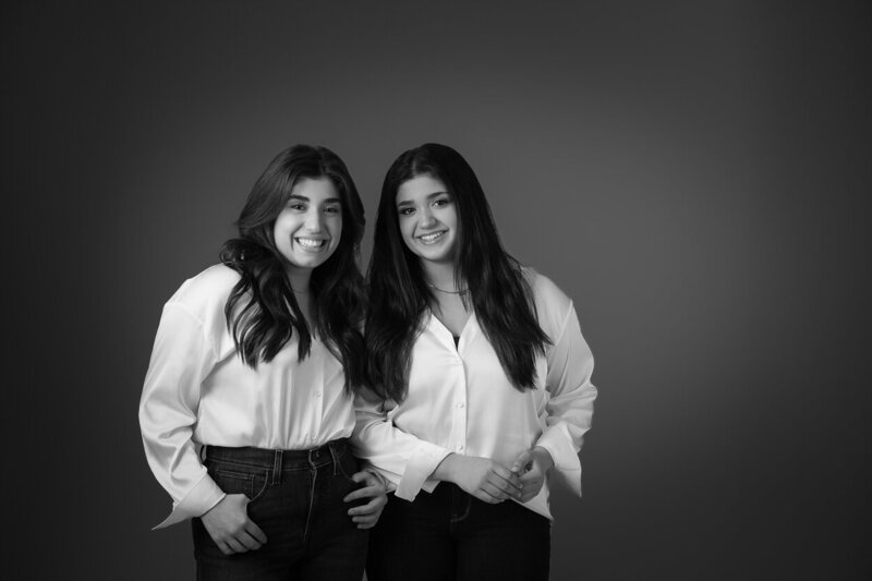 Teenage sisters smiling at the camera in black and white image created in Charlotte NC Studio of Insley Photography