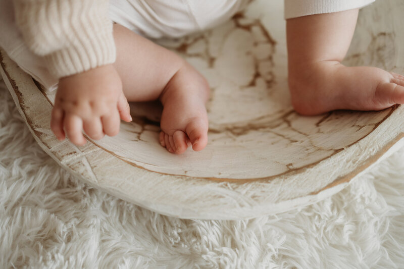 Eight month old baby girl sits in a wooden bowl during her milestone session in Denver