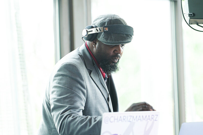 DJ Walt from Charizma Entertainment mixing live at Chicago event in gray suit and cap