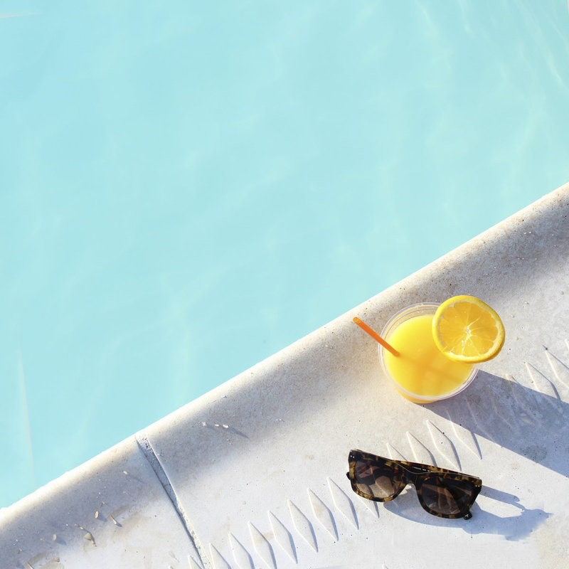 sunglasses and a drink next to a pool