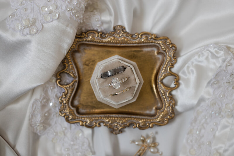 Close-up of diamond engagement ring and wedding band on a soft velvet surface, reflecting natural light.