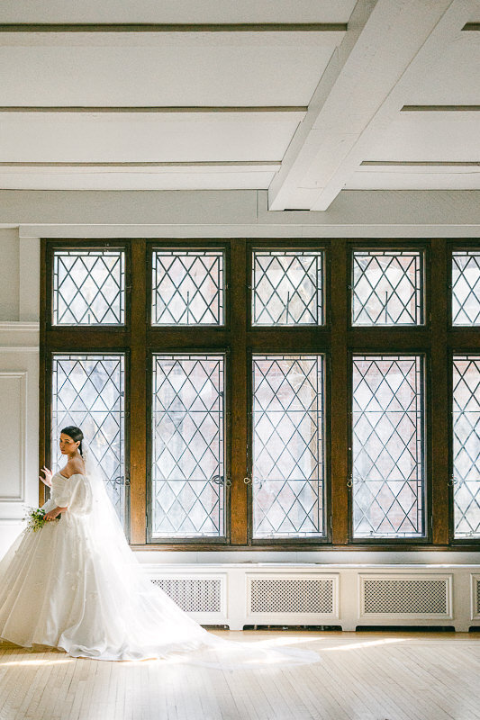 A gorgeous and romantic bride in her stunning wedding gown, is standing near the windows of Club Atwater. Best Montreal Wedding Venu in Montreal.