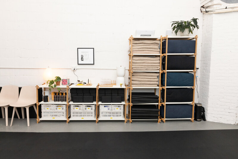 Held Space studio amenities pictured: yoga blankets, props and more organized in wooden shelves.