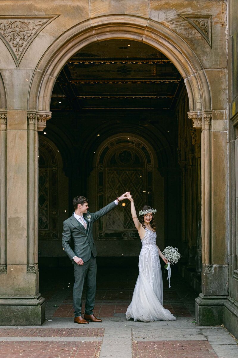 A bride and groom take photos at the Bethesda Terrace arches