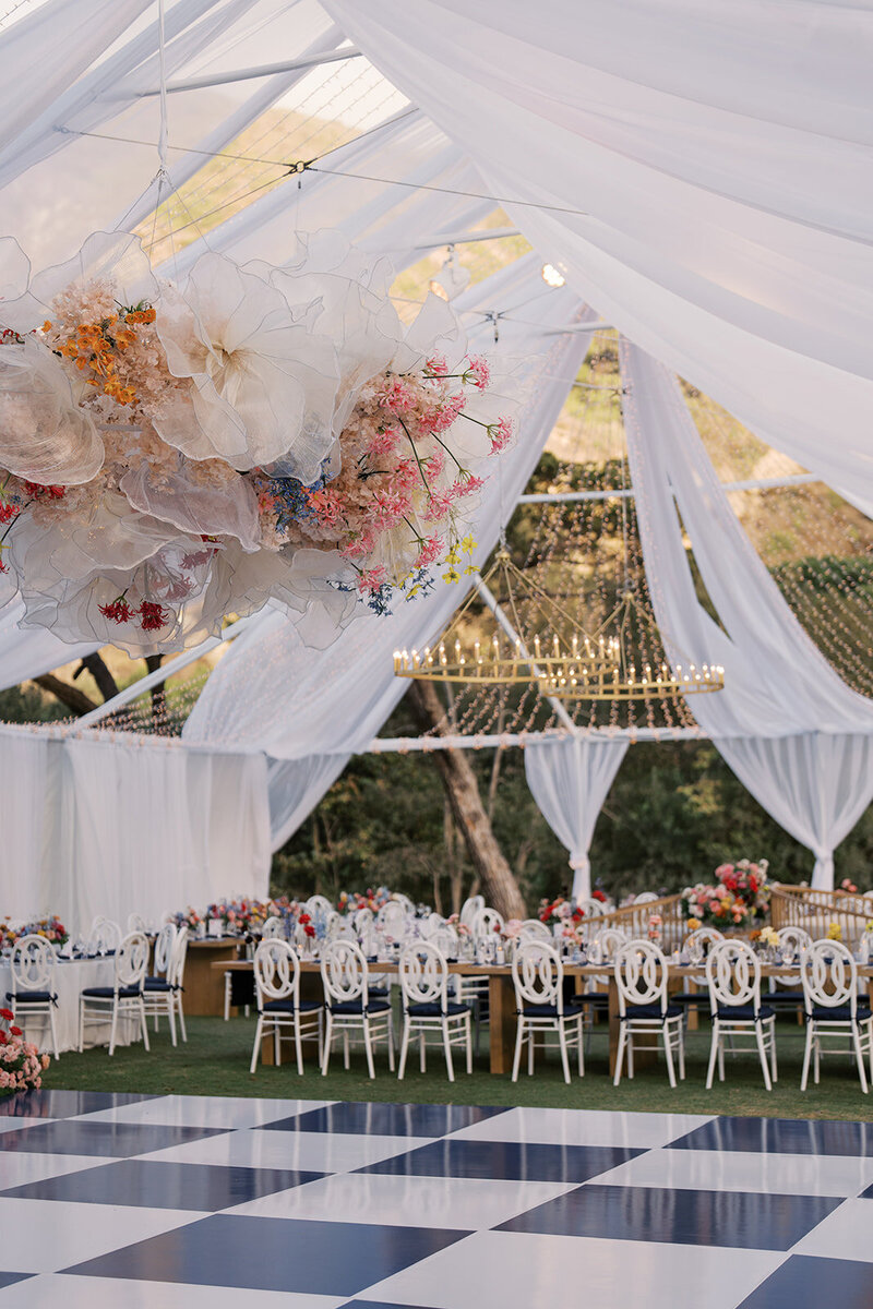 Wedding reception tables set up in an outdoor arched corridor overgrown with ivy