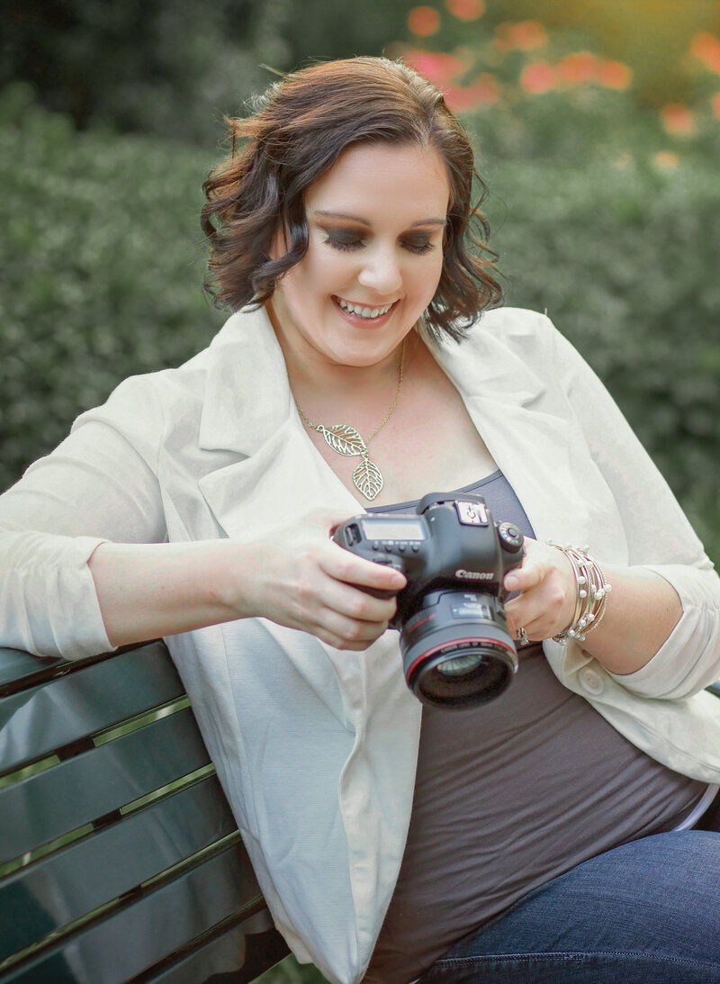 Ella Grace Richards, a Chicago-based wedding and event photographer, smiles while looking down at her camera, reflecting her passion for storytelling through elegant and authentic imagery.