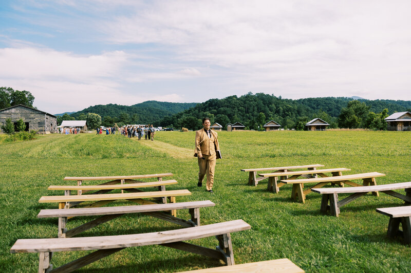The officiant leads the wedding guests to the ceremony site at the rustic and natural wedding venue Paint Rock Farm in North Carolina.
