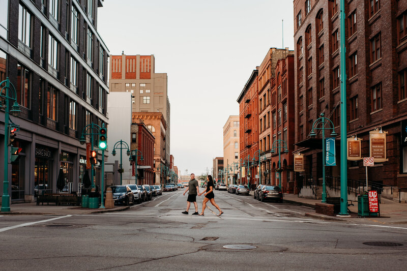 Man and woman walking across the street during their Milwaukee engagement