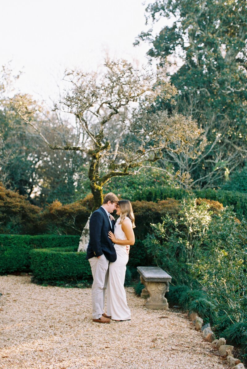 Woman holding hands with man looking back at camera in front of a white mansion