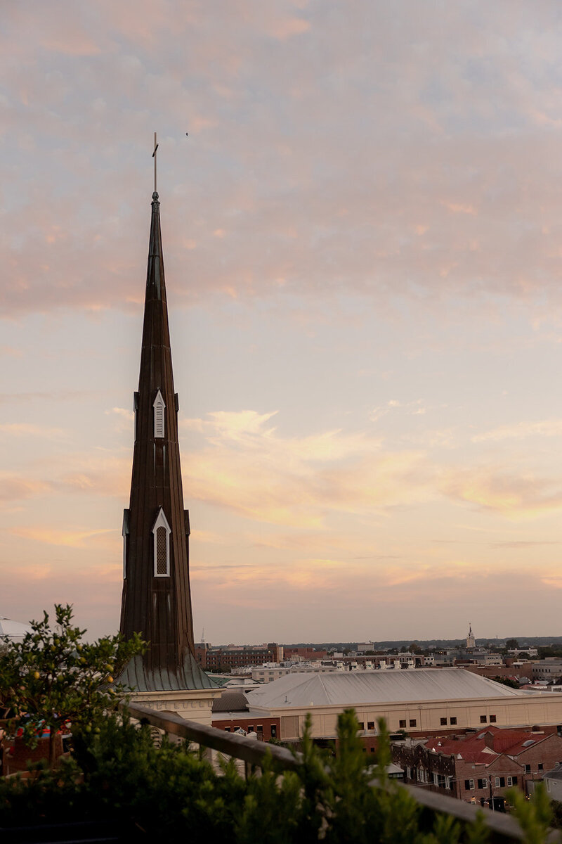 Sunset photographed from the Dewberry hotel rooftop during a wedding. Citadel Square Church tower to the left and multiple roofs and other building tops on the right