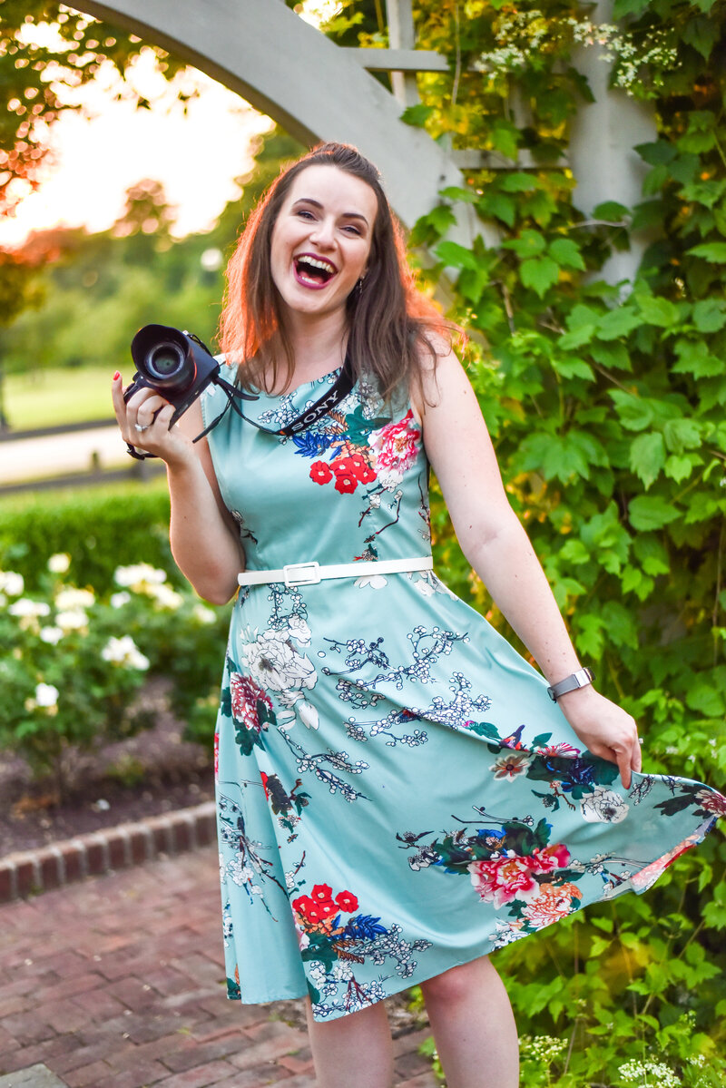 Amy Hord holding her camera and laughing while she twirls her dress.