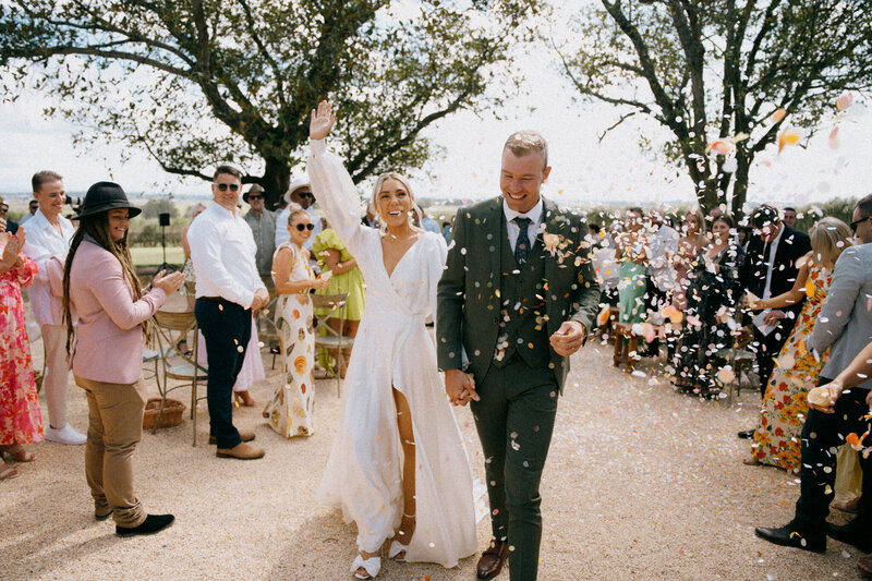 Bride and groom walking down the aisle with confetti at their Wallalong house wedding, Hunter Valley