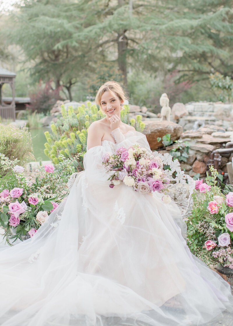 Wedding Photographer, beside a fountain outdoors , a bride smiles, she has a wedding ring and flower bouquet