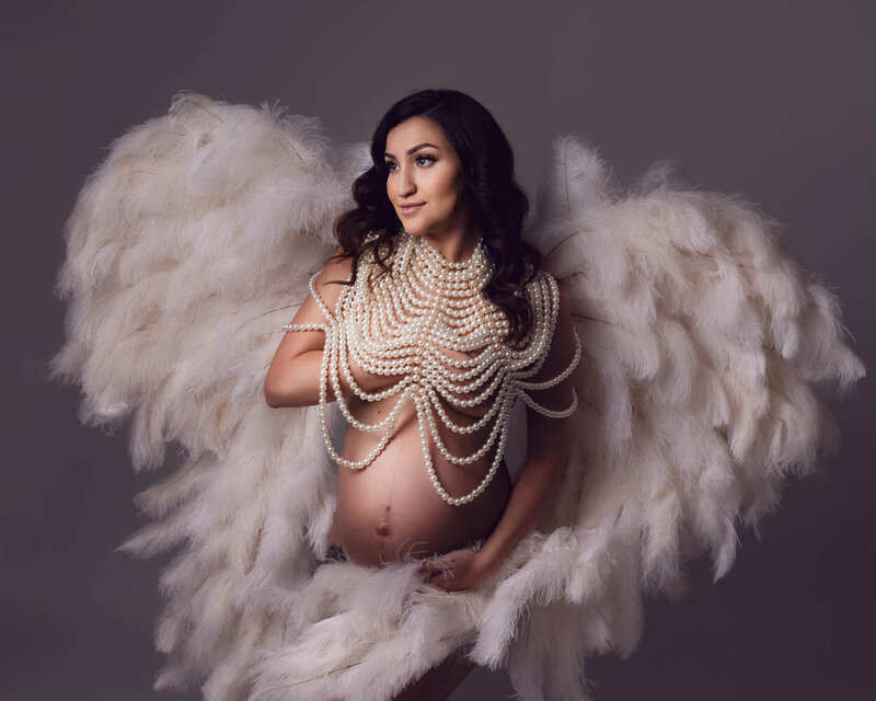 maternity photo session, mom wearing white feathers with a pearl necklace.