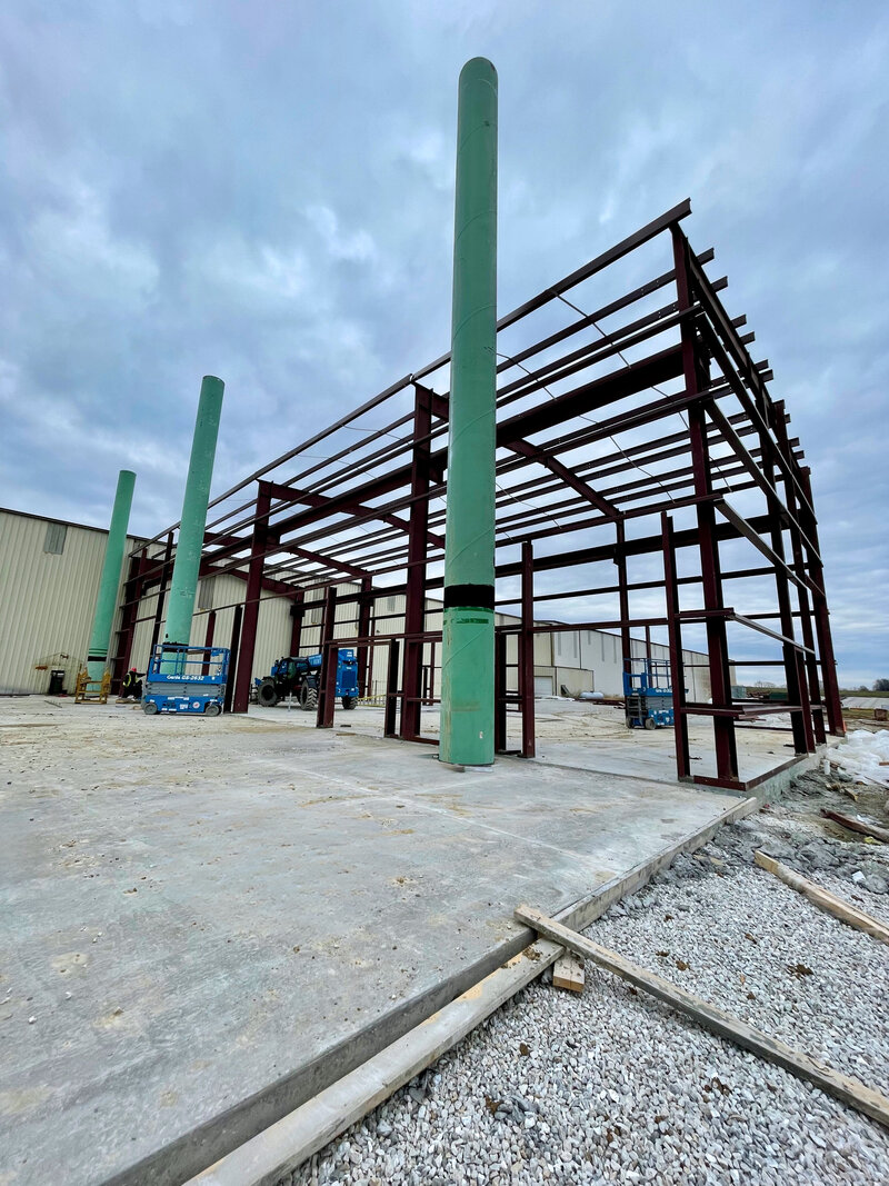 Steel framework under construction for an industrial building with welded structural beams and steel erection in progress.