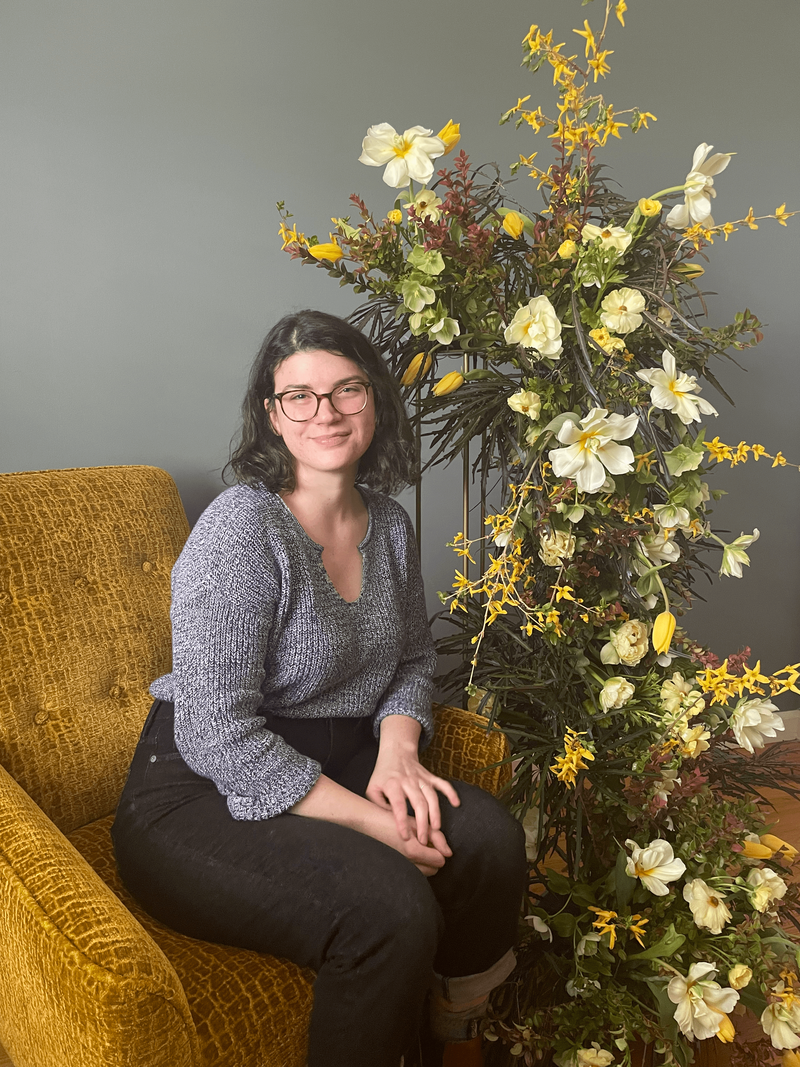 Jillian Santora sitting in front of yellow themed floral display. Owner of Jessamine Floral and Events, in New Jersey & Philadelphia