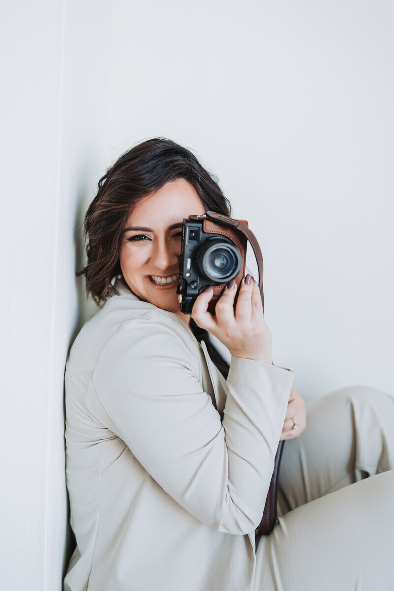 woman smiling at the camera while holding camera up to her eye
