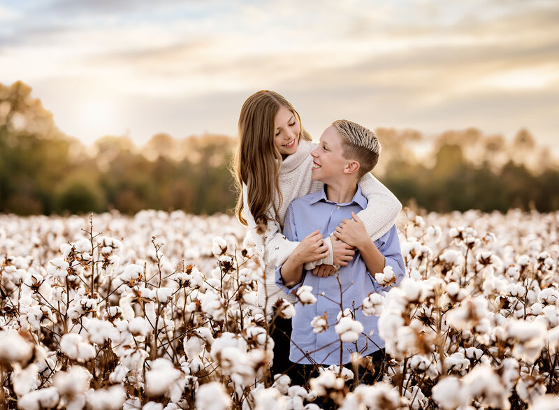 Cotton field near Atlanta, GA of siblings hugging and looking at each other. Mini session photos taken by Jenni Nikki Photography.