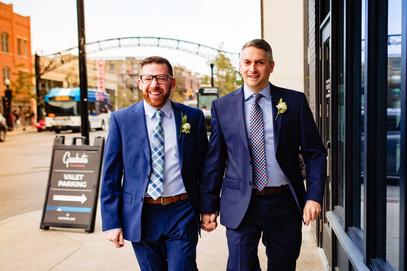 Two grooms holding hands while walking down the street in Columbus Ohio during their wedding
