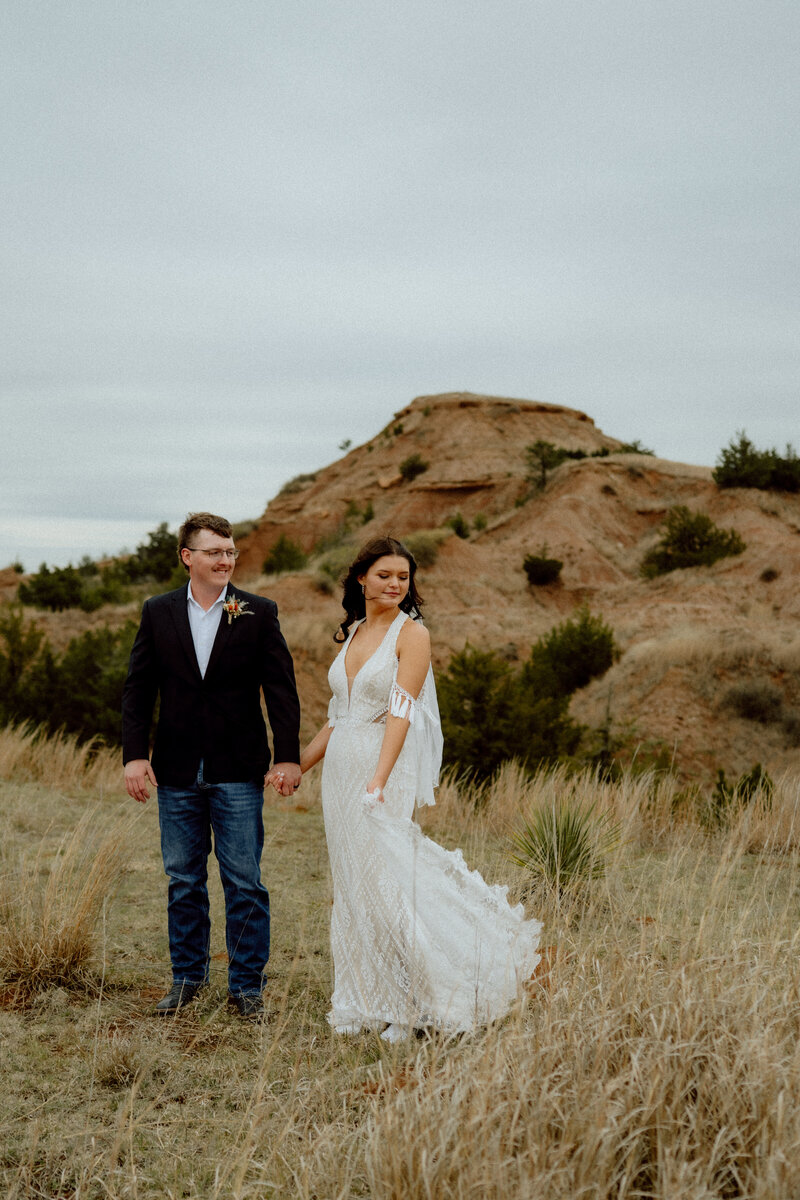 bride flowing her dress in the wind as groom watches