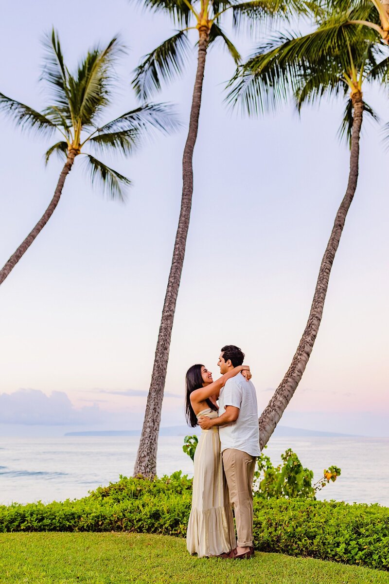 couple posing beneath two palm trees in wailea maui