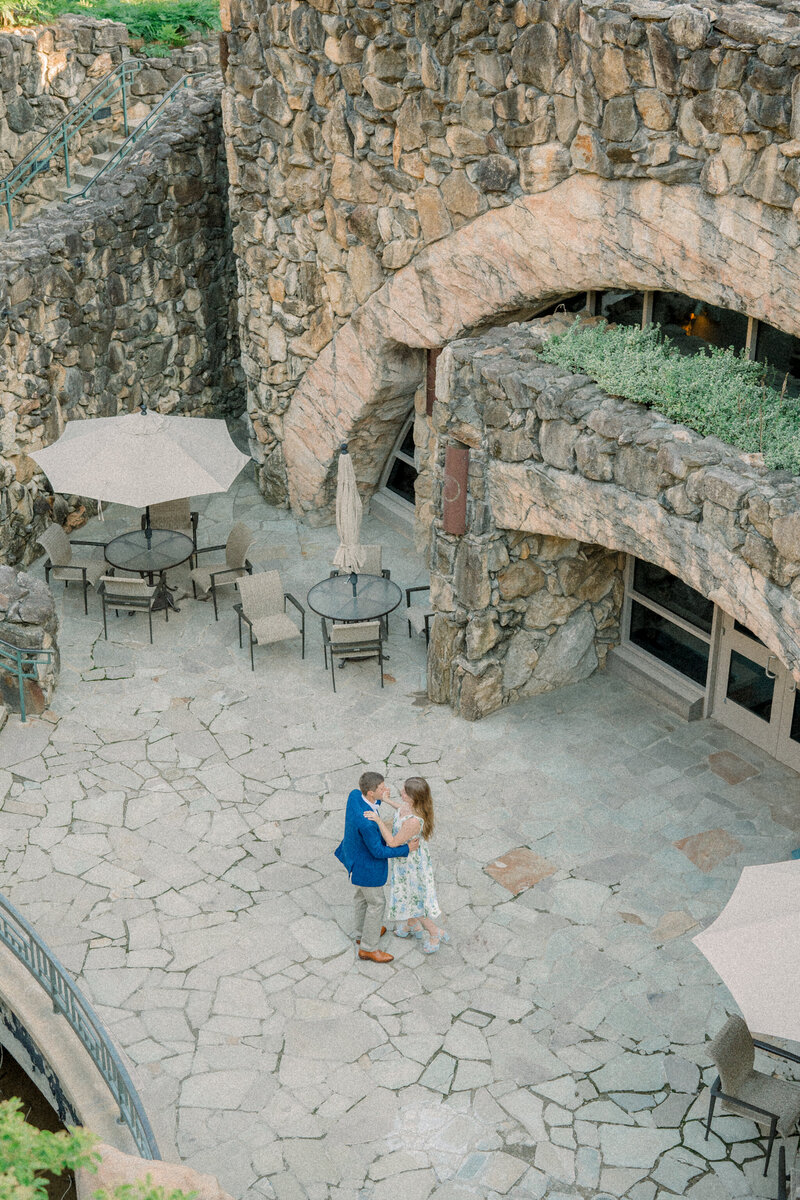 A couple shares a romantic dance in a stone courtyard, surrounded by rustic rock archways and patio tables. Captured in a timeless, editorial style by a Richmond, VA photographer.