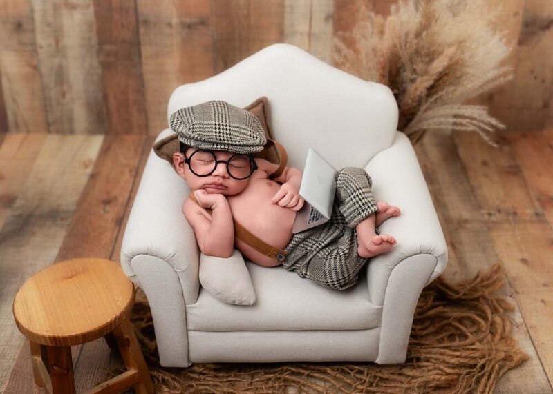 newborn-baby-on-tiny-couch-prop-newsboy-outfit