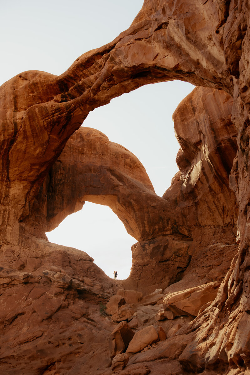 Bride and groom standing in double arch on their elopement day in arches national park, utah