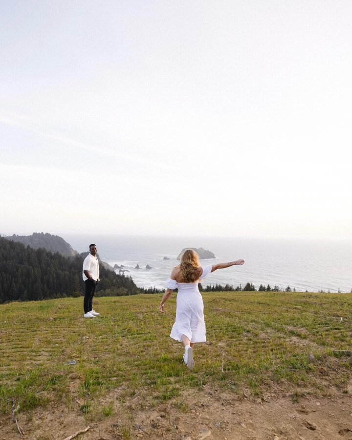 Bride running toward groom on coastal cliffside in California – romantic engagement session overlooking the Pacific by Madison Dodd Photo