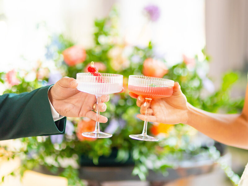 wo coupe glasses cheersing with raspberries in drinks