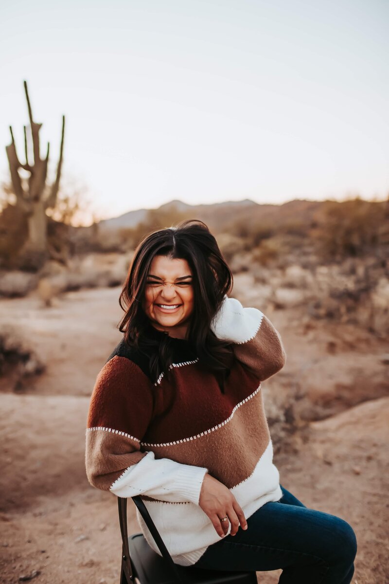 woman sitting on a chair smiling in the desert
