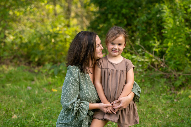 mom smiling at daughter who is smiling at camera