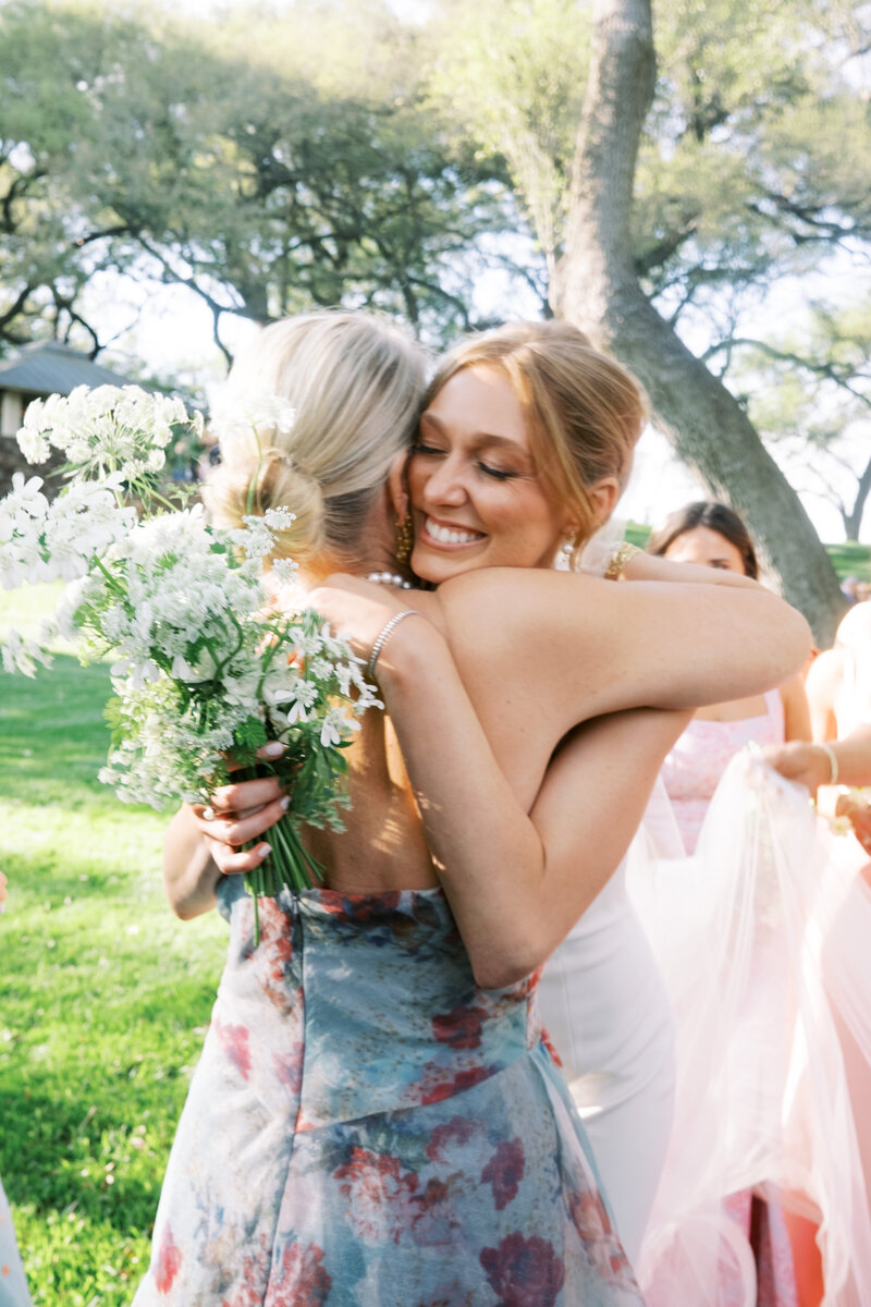 Film photo of bride hugging bridesmaid in a floral dress