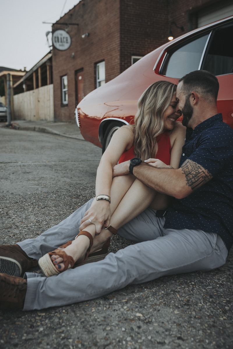 couple sits against a Chevelle for their engagement photos at Loflin Yard in Memphis