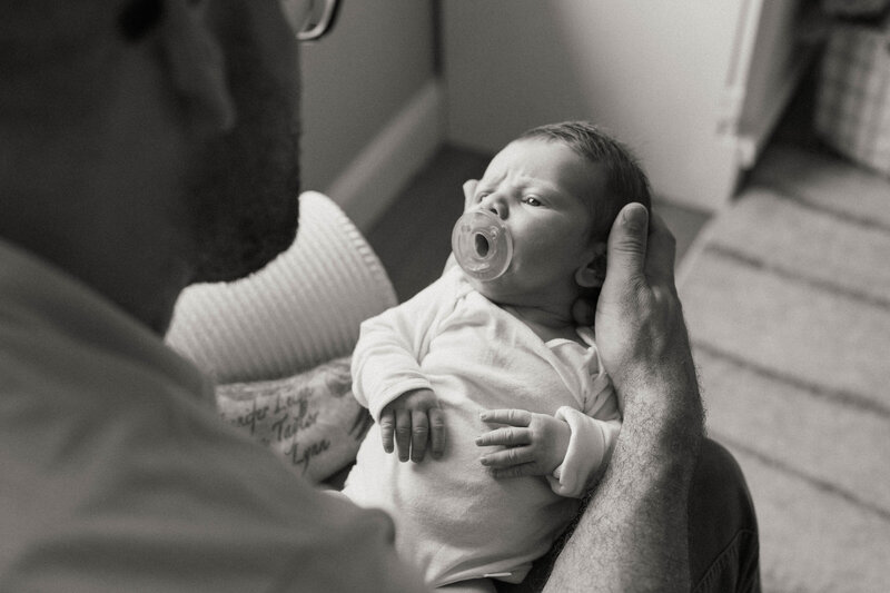 Newborn son looking up at father
