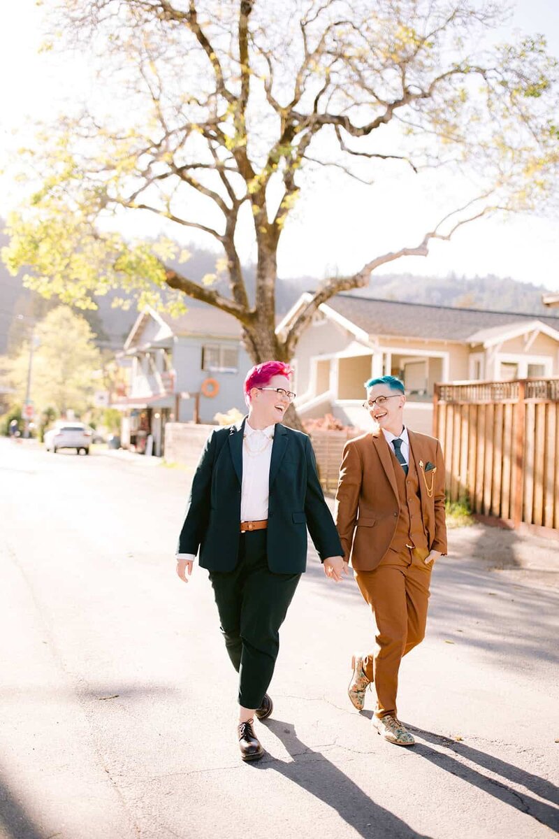 Two women wearing suits walking down street on their elopement day. 