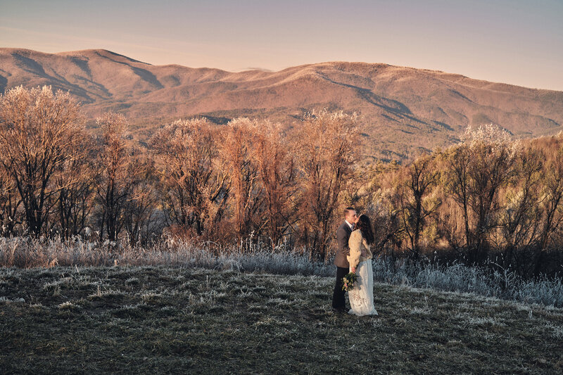 Eloping couple kisses with snowy mountains in the background