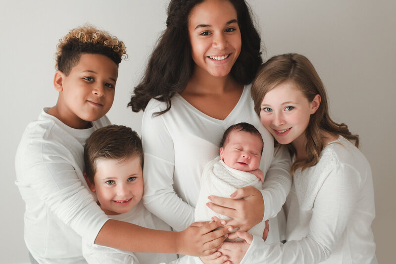 blended family kids holding new baby brother