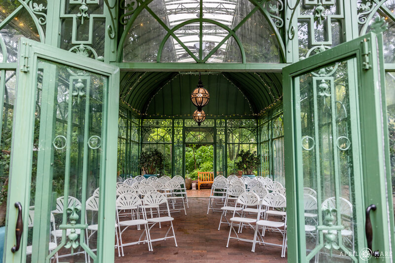 Looking inside the doors at a wedding ceremony set up inside the  Woodland Mosaic Solarium at Denver Botanic Gardens