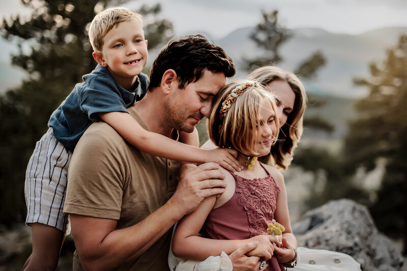 A father leans his head into is young daughter's while giving his son a piggy back in Rocky Mountain National Park.