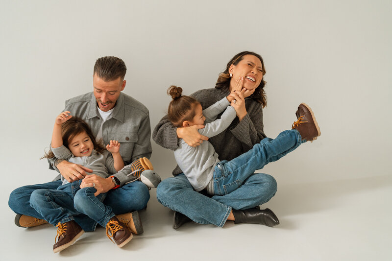family in all white studio laughing together