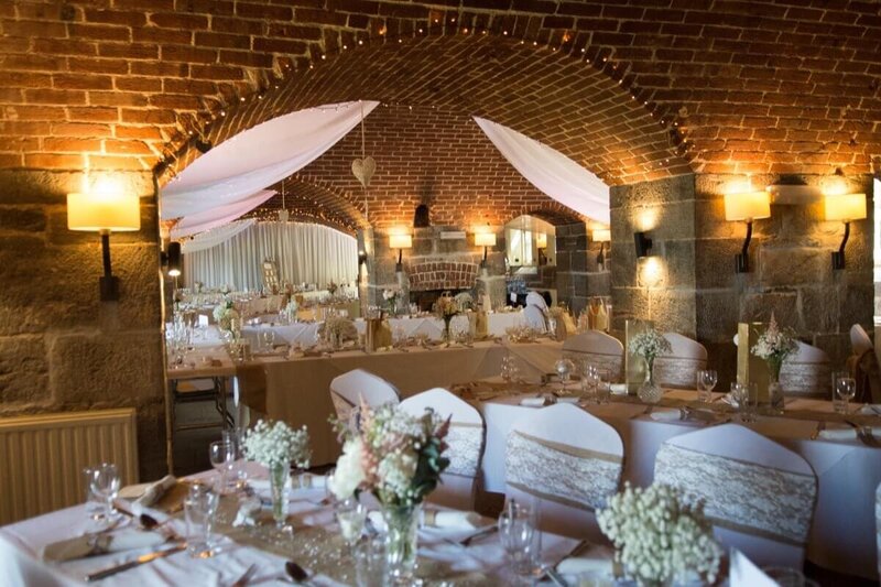 Long tables set up with decor and bottles of wine, ready for wedding guests