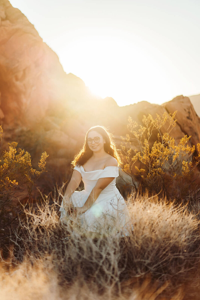 The girl in a white dress is sitting down in the desert