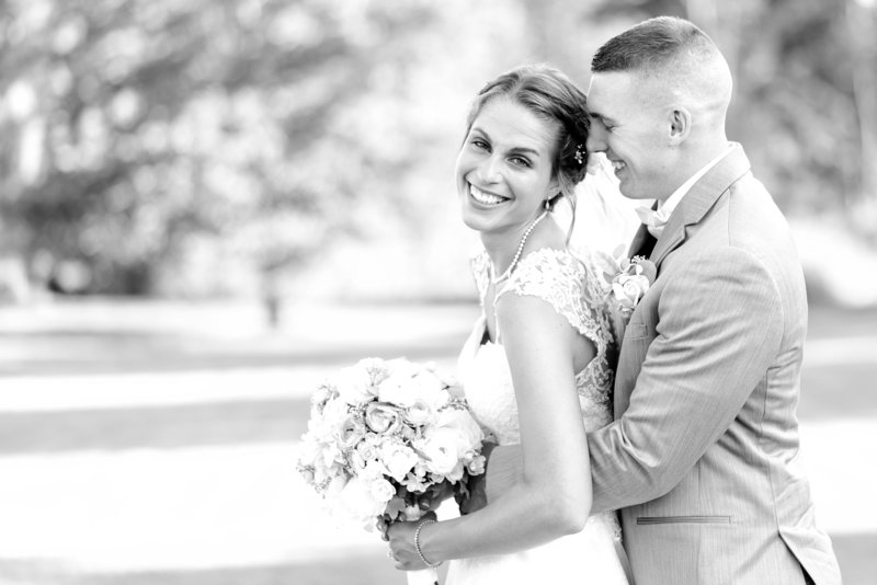 Black and white photo of smiling bride with her groom.